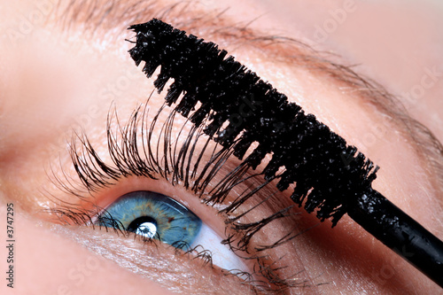 the girl is putting a mascara on eye lashes