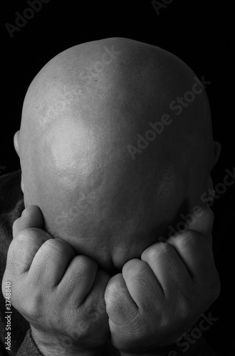 A depressed man pressing his face into his folded hands
