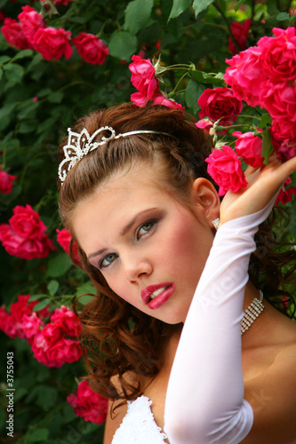 Beauty Girl in Wedding Dress in the red roses