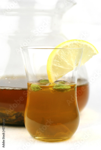 the pot and glass of green tea with lemon and cardamom
