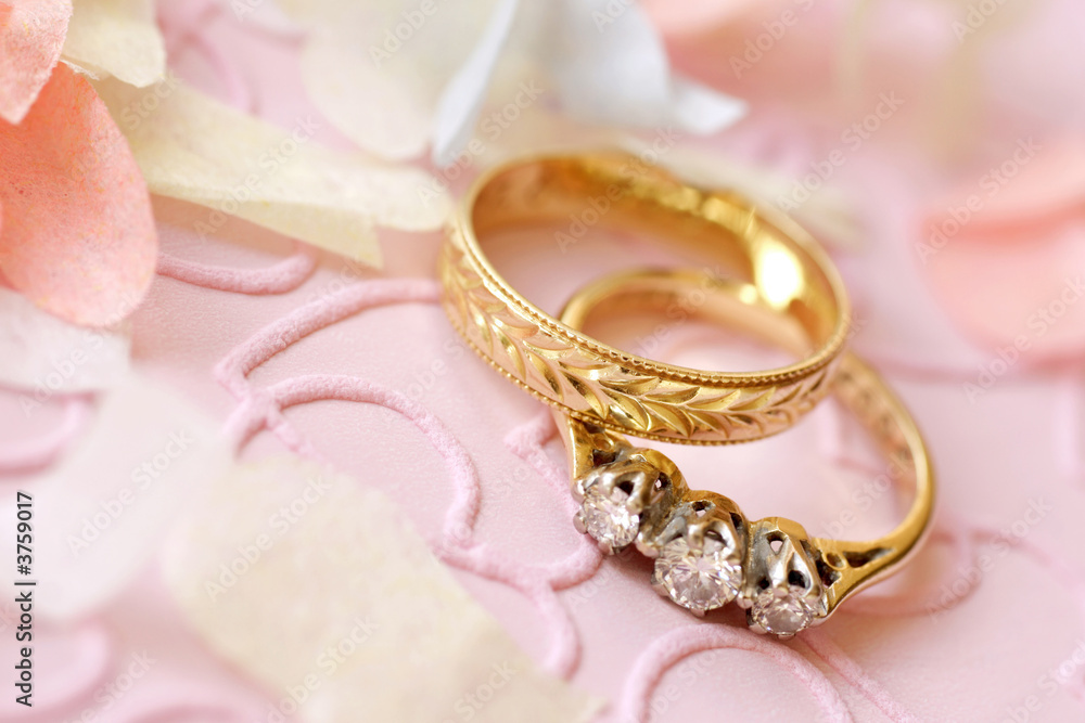gold wedding ring and engagement ring surrounded by confetti