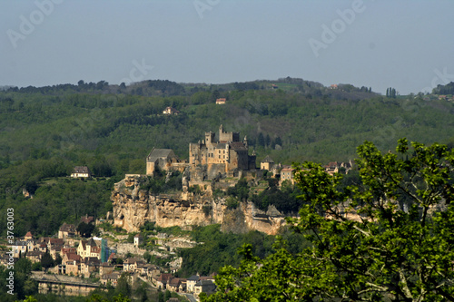 castle on side of rock with village below, france