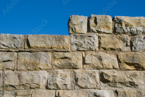 Old sandstone wall with stepped or raised section and blue sky