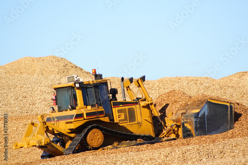Large earthmover with scoop of wood chips