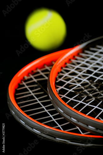 tennis-ball in motion and two racket on black background