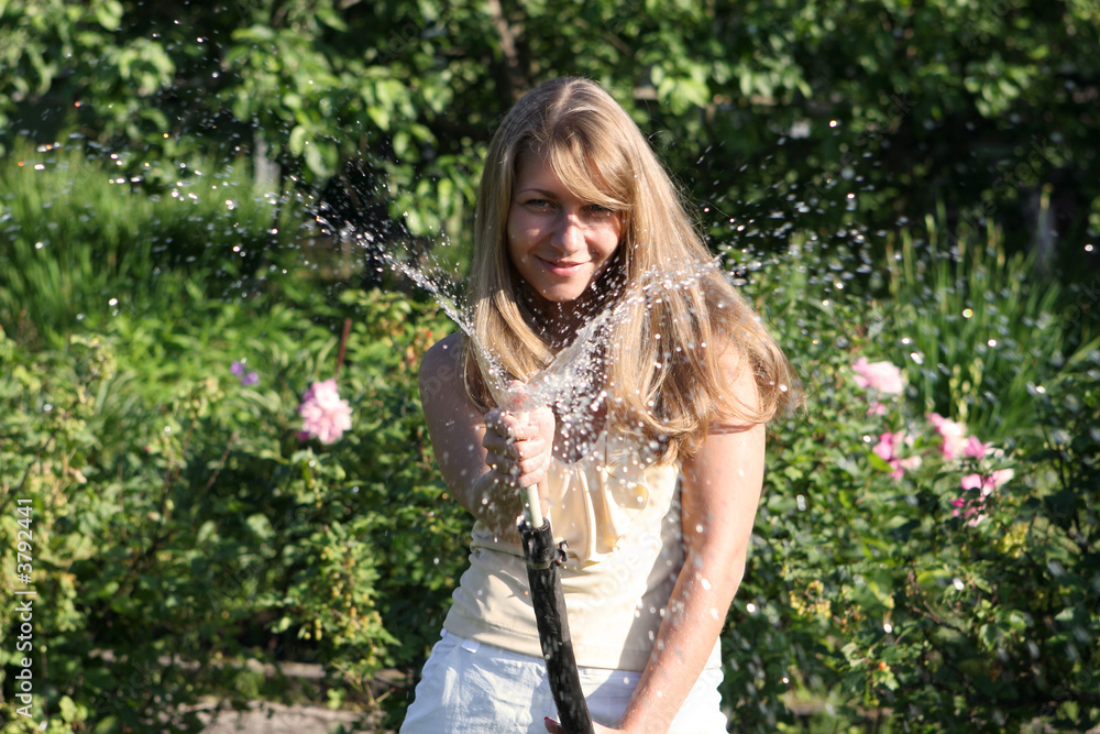 Beautiful girl in the garden with hose