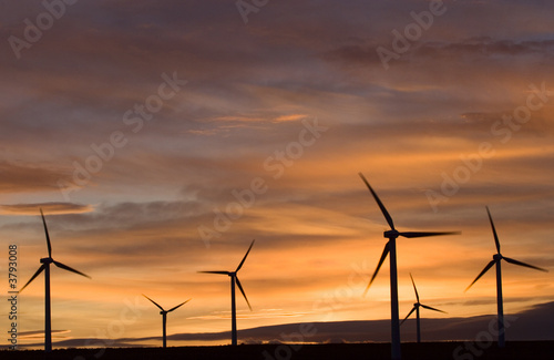 Wind turbines against an orange sunset.