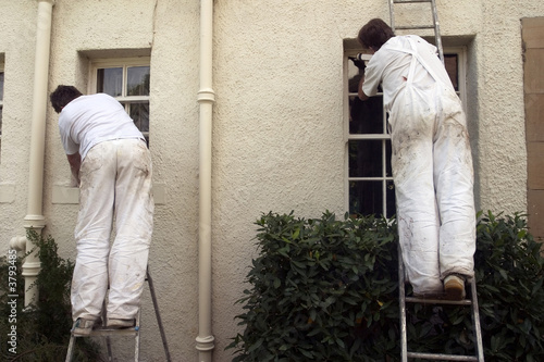Two painters decorating the exterior of a house.