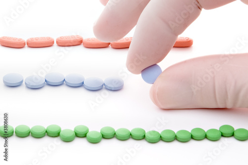 three rows of red green and blue pills and hand picking blue one photo