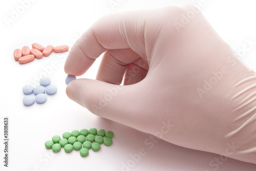 Hand with glove picking one blue pill photo