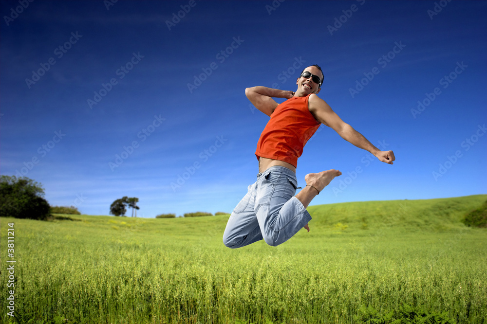 Man jumping on a green meadow with a beautiful cloudy sky Man jumping on a green meadow with a beautiful cloudy sky