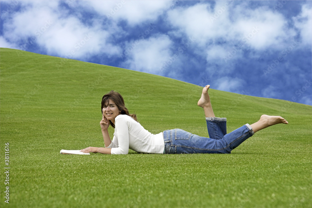 Beautiful woman lying on the grass and reading Beautiful woman lying on the grass and reading