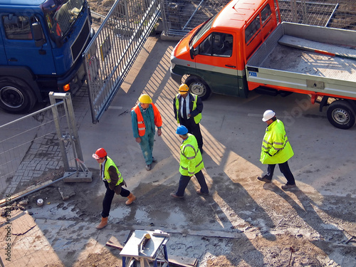 Constructionworkers with cars walking on a buildingplace