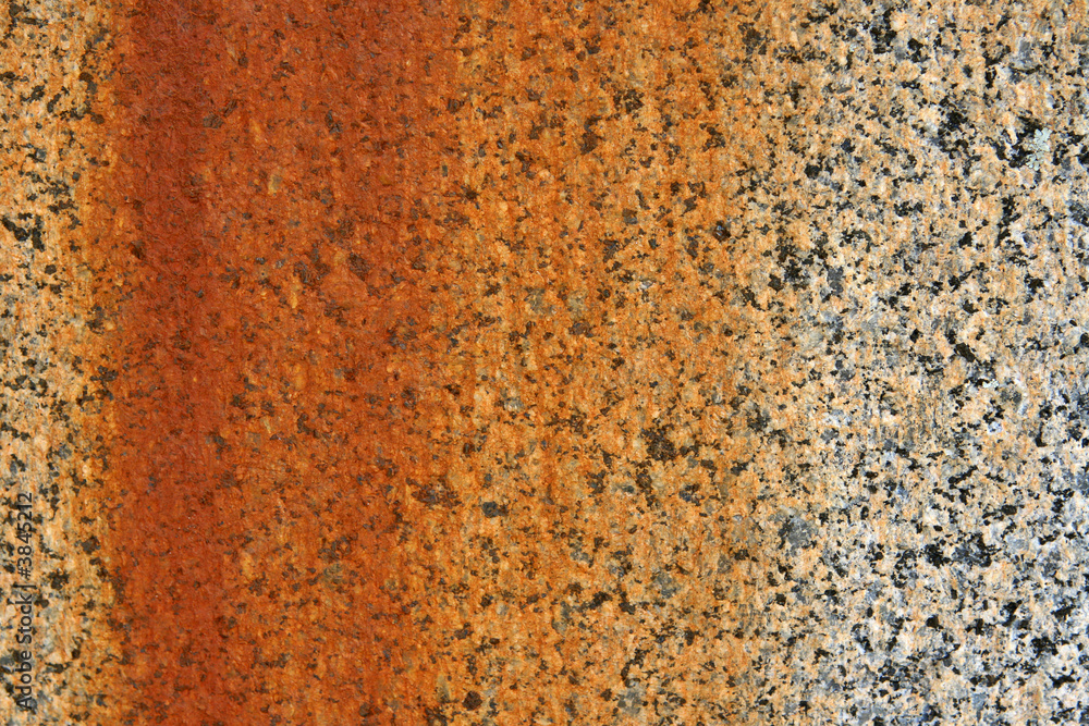 A stone granite wall showing stains created from rusting metal. A stone granite wall showing stains created from rusting metal.