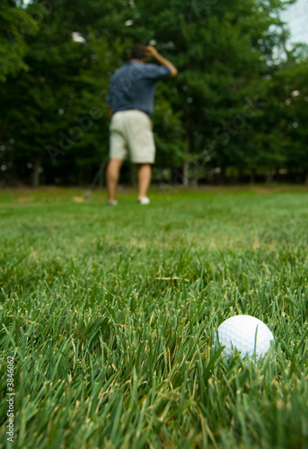 Camera zooming on golf ball with puzzled golfer in the back