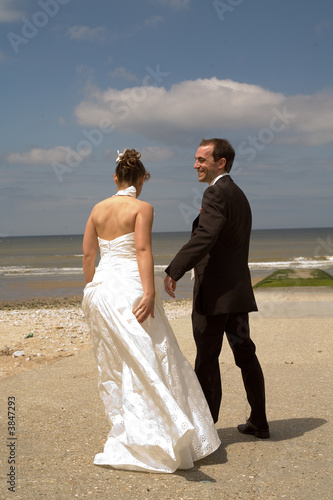 mariés se tenant la main devant la mer © Christophe Denis