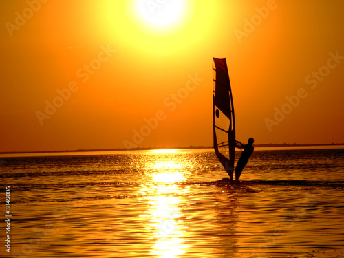 Silhouette of a windsurfer on waves of a gulf on a sunset