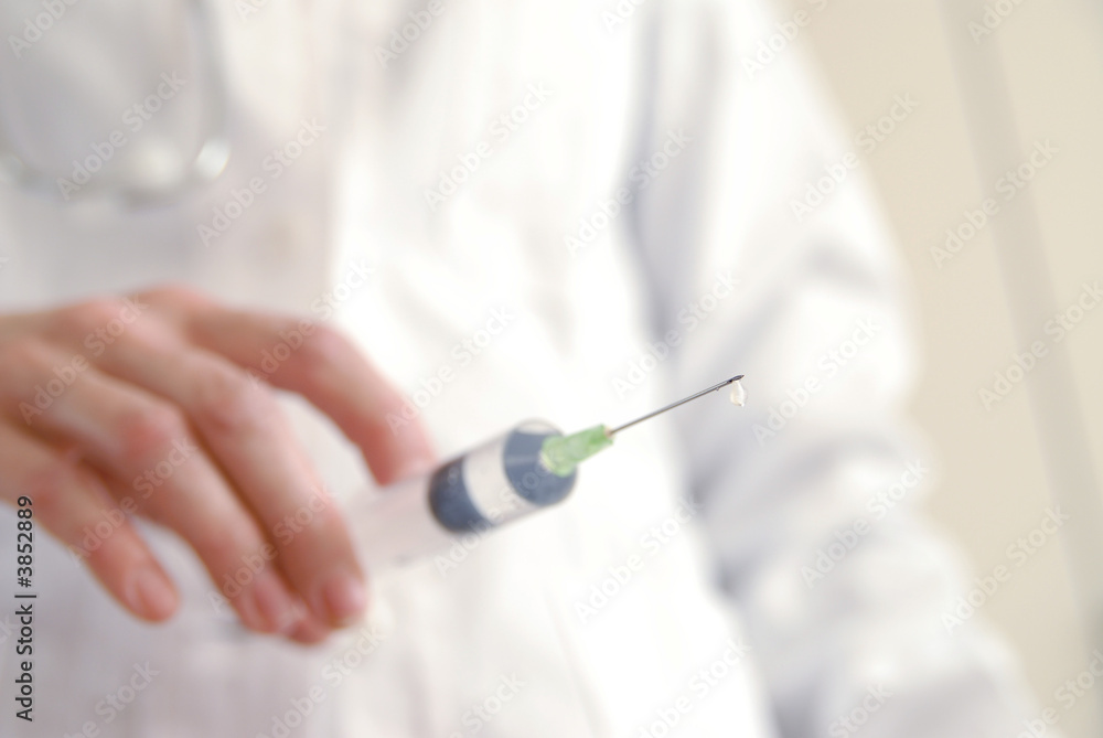 Docator holding with one hand a medical syringe with drop Docator holding with one hand a medical syringe with drop