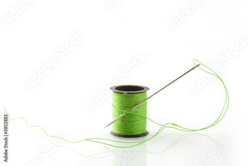 green thread on a spool with needle