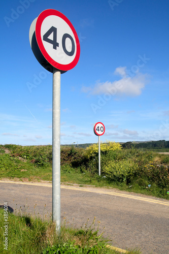 Vertical view of two 40 miles an hour signs on a country lane.