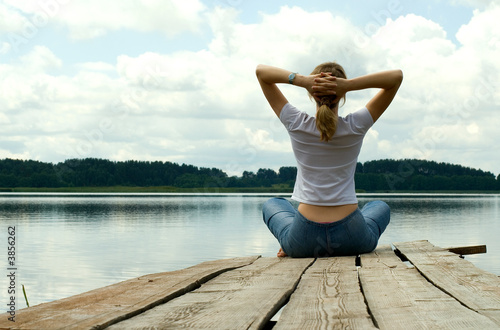 The girl is engaged in meditation on coast of lake