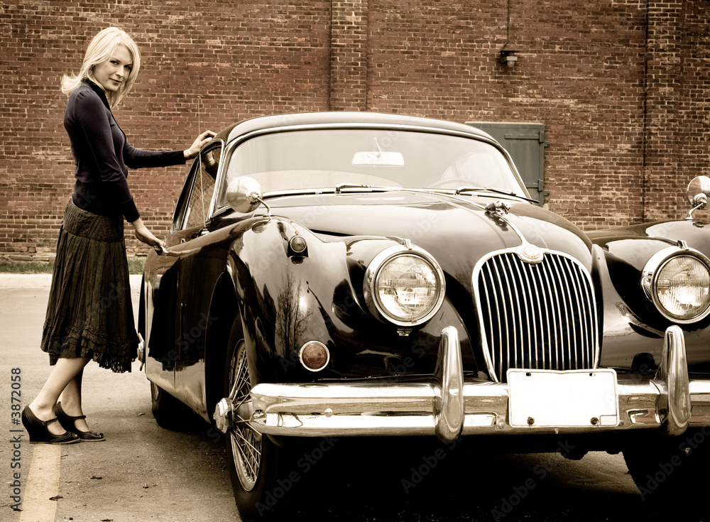 Fototapeta premium A beautiful blond woman getting into a classic car