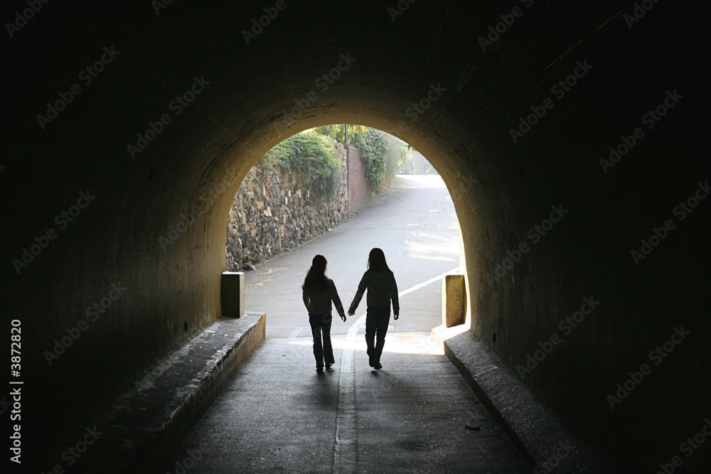 Silhouette of two young girls in a tunnel