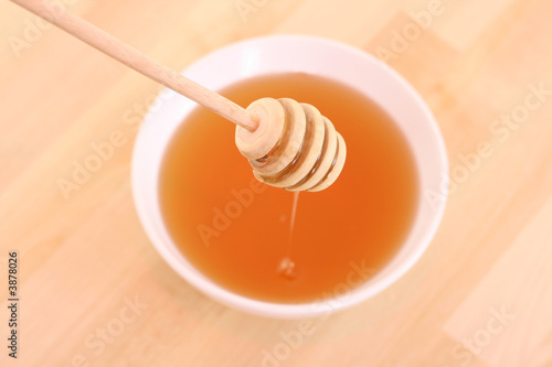 bowl of honey with wooden stick on table