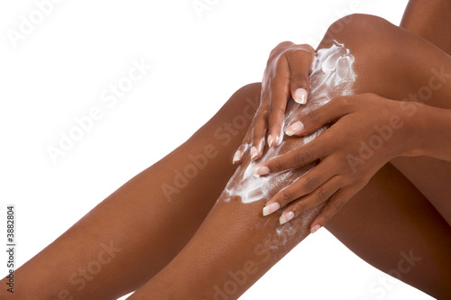 female putting Moisturizer on her legs (close up)