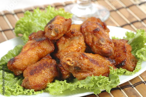 Spicy hot barbecued wings on bed of lettuce.