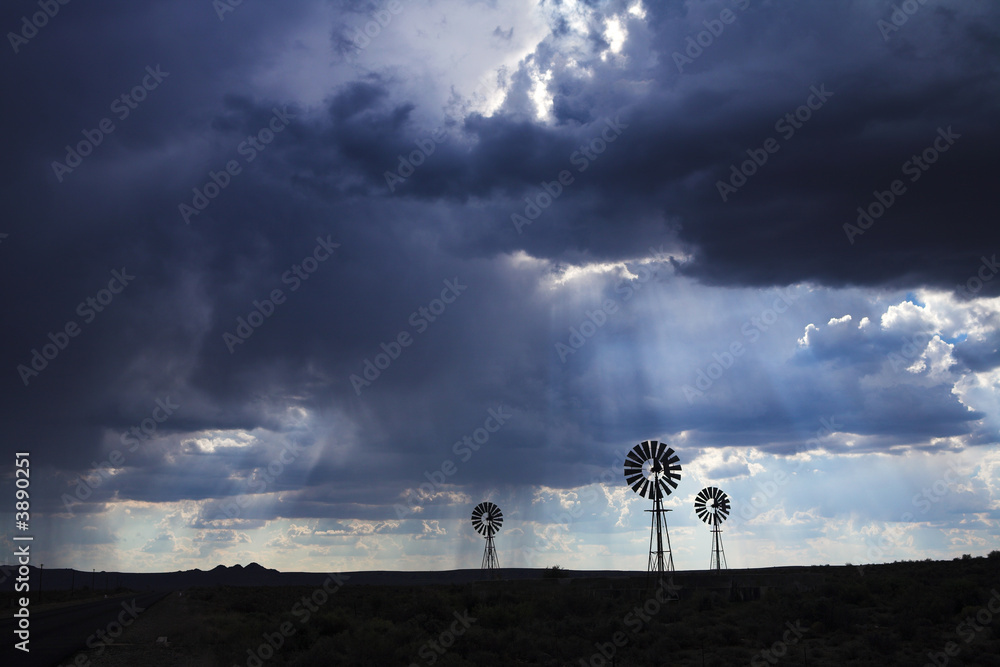 Three wind pumps silhouetted against the skyline