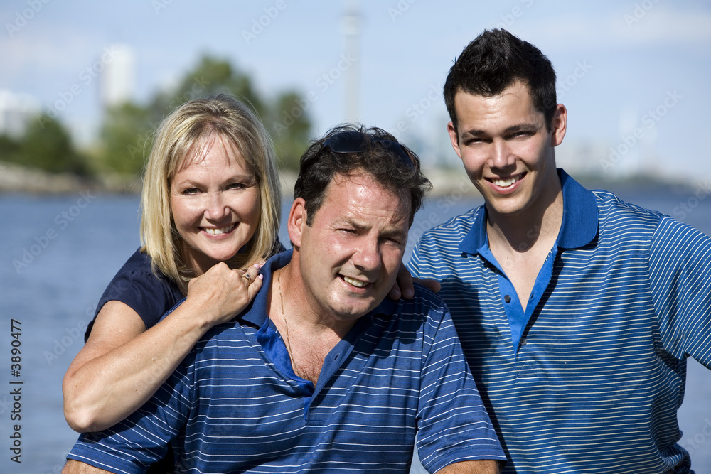 family of three posing together close to the lake family of three posing together close to the lake