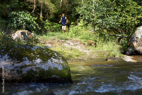 Läufer auf Waldweg neben einem kleinem Fluss