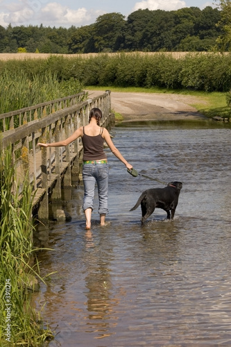A country girl and her black dog cross a ford in the summer