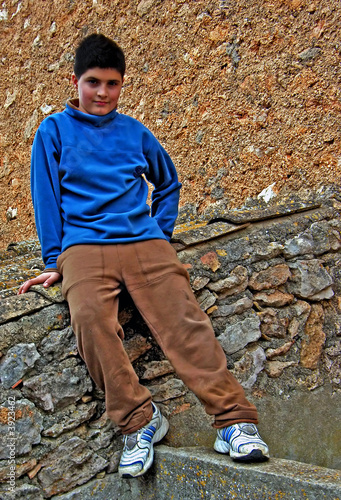 Canvas Print Prankish boy sitting over a wall