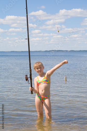Girl holding a fish caught on a fishing line with clouds