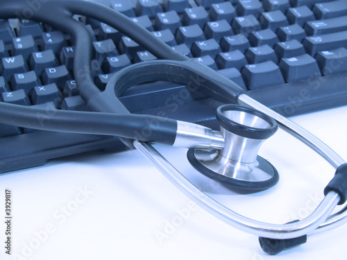 Stethoscope next to computer keyboard - blue