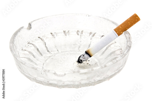 burning cigarette in glass ashtray