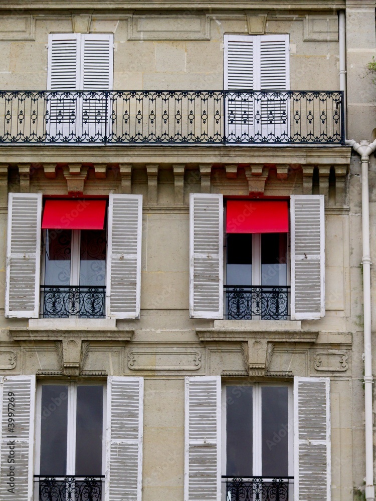 Façade de paris, stores rouges et  volets blancs.