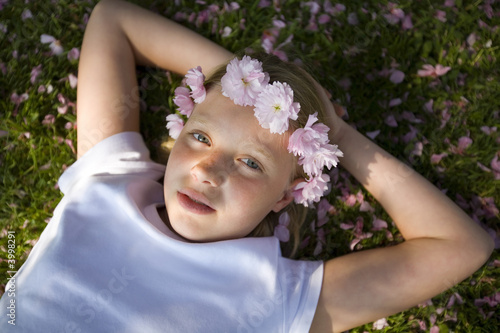girl with cherry blossom in her hair lying down the  grass
