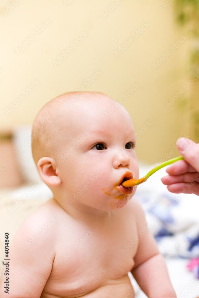 Mother feed baby by mashed melon and carrot with plastic spoon Mother feed baby by mashed melon and carrot with plastic spoon