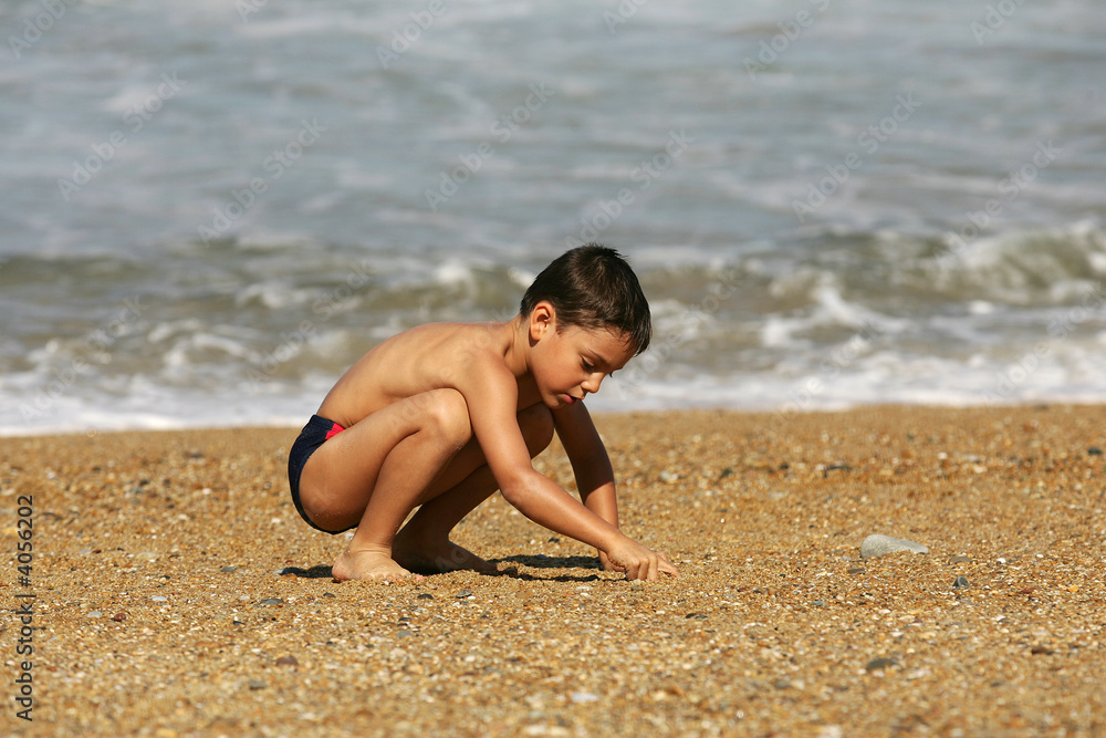 petit garçon qui cherche dans le sable