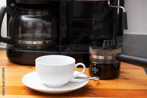 Closeup of white coffee cup next to coffee machine