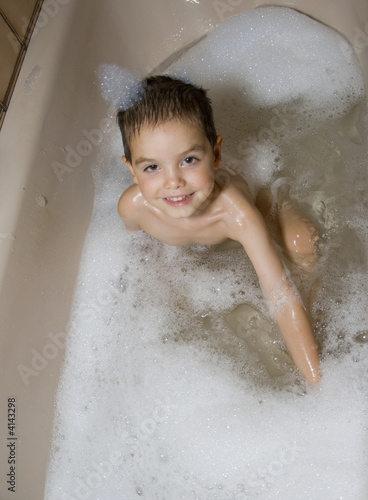Kind lacht im Schaum der Badewanne
