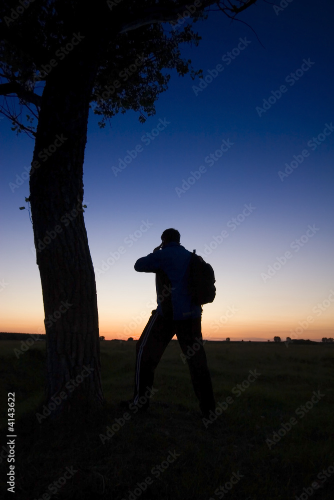 Obraz premium A man's silhouette in the sunset with a tree