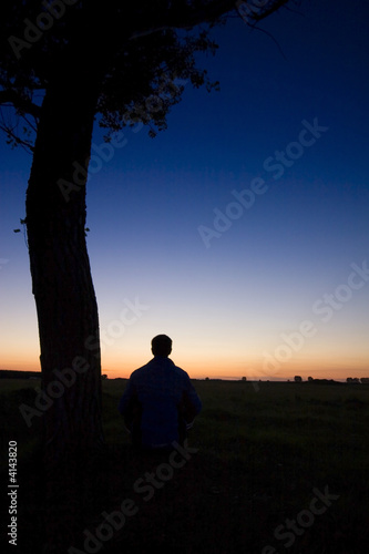 A man s silhouette in the sunset with a tree