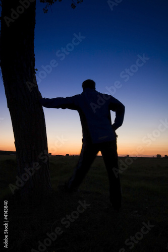 A man's silhouette in the sunset with a tree