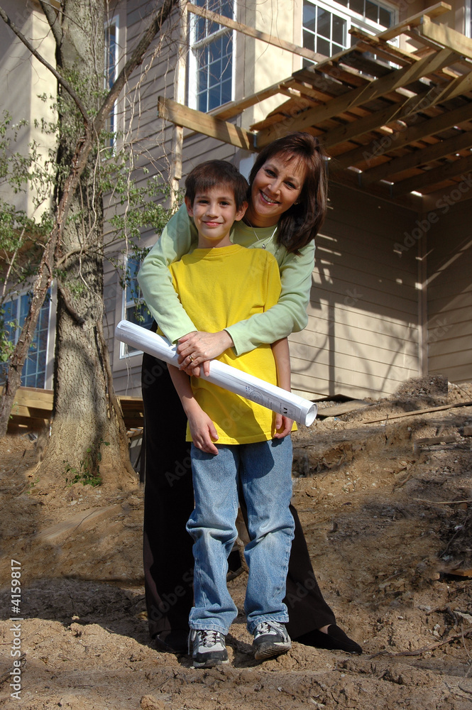 Mother and son in front of house under construction Mother and son in front of house under construction