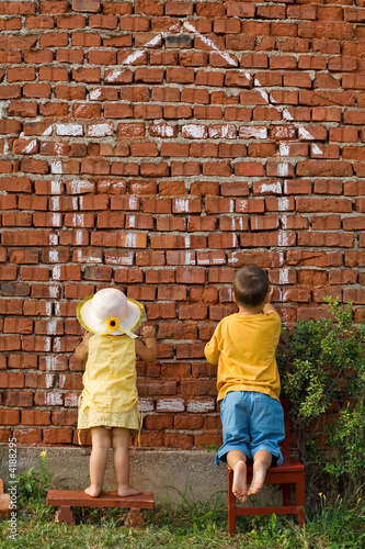 Two kids drawing a home