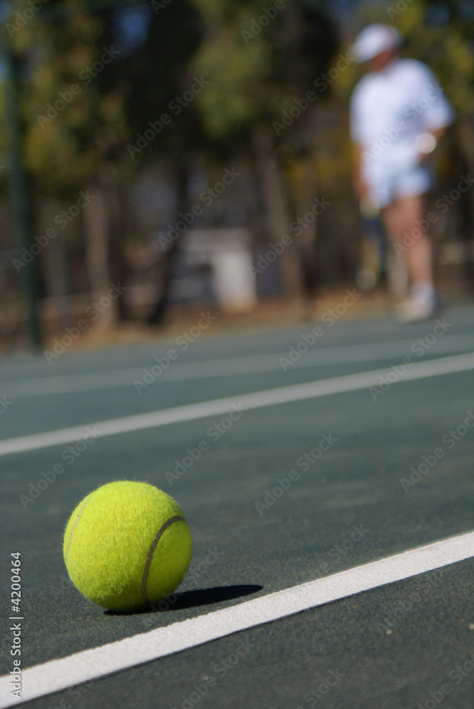 Tennis ball on the court and tennis player out of focus